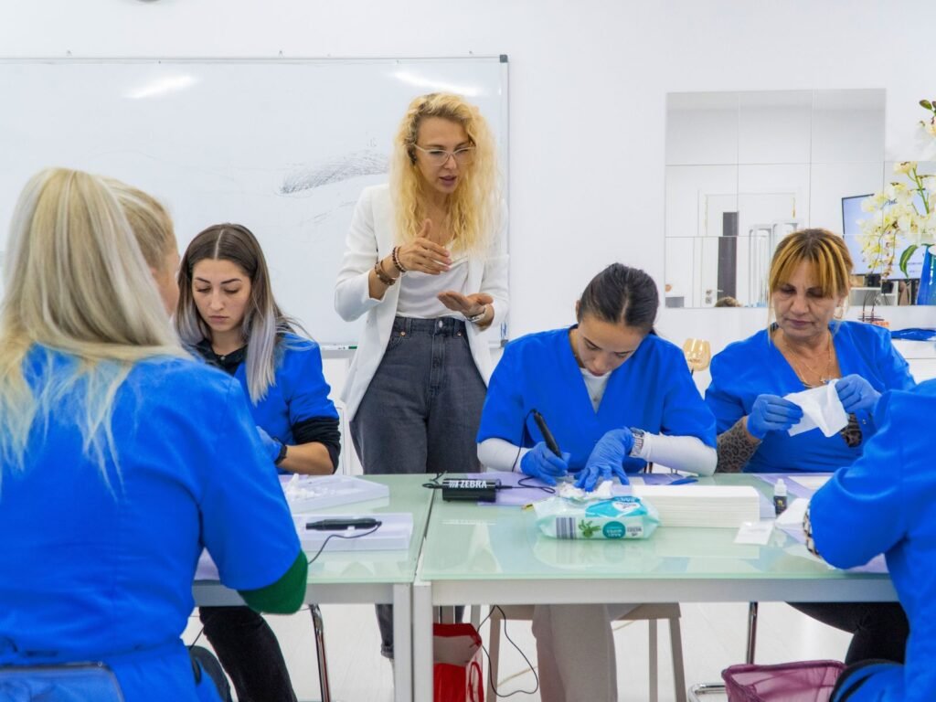 Cursanți ai Colegiului de Estetică în timpul unei sesiuni teoretice la masa de lucru